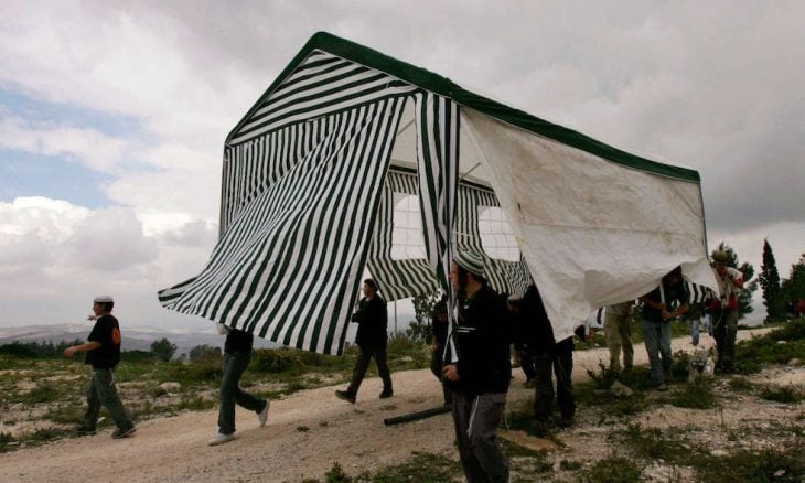 ヨルダン川西岸北部の元入植地ホメシュの前哨基地にテントを運ぶ入植者たち